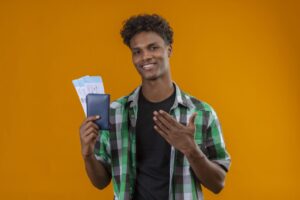 Direito do trabalho: A imagem mostra um jovem sorridente segurando uma carteira de trabalho azul diante de um fundo laranja vibrante. Ele transmite entusiasmo e orgulho, sugerindo que acaba de conquistar um novo emprego ou uma oportunidade profissional importante. A composição colorida e o tom positivo da foto fazem dela uma excelente escolha para ilustrar temas como início de carreira, primeiro emprego, conquista profissional, valorização do trabalho formal e direitos garantidos pela CLT.