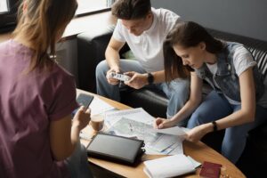 investário A imagem mostra três pessoas reunidas em torno de uma mesa, analisando documentos, mapas e anotações. O clima é de organização e levantamento de informações, remetendo a um **processo de inventário**, no qual são avaliados e registrados bens, propriedades ou dados importantes para planejamento e tomada de decisões.